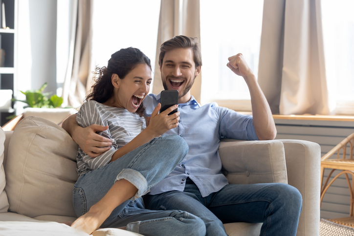 Overjoyed surprised young couple looking at phone screen
